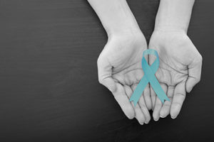 Hands holding teal ribbon